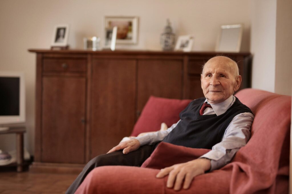 Man in Gray Dress Shirt Sitting on Red Sofa